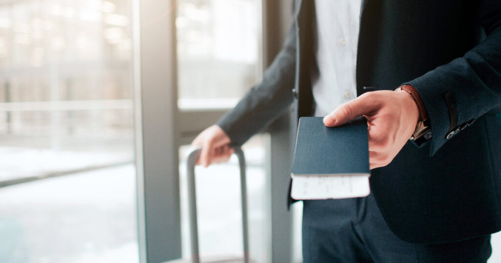 Persoon op een luchthaven met een koffer en paspoort of gouden visum in de hand.